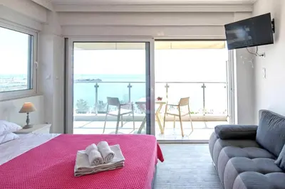 a bedroom with a bed with a pink blanket and a couch at Breathtaking seaview studio in Athenian Riviera in Athens