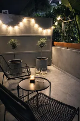 two wine glasses sitting on a patio with lights at Athenian Coastal Urban Living in Athens