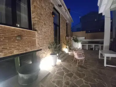 a patio with chairs and a table and a brick wall at Stoa House Airport in Koropíon