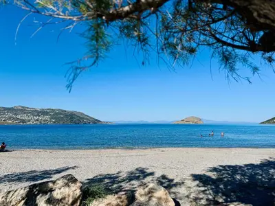 a beach with people swimming in the water at Seashore Happiness Apartments in Porto Rafti