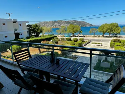a balcony with a table and chairs and a view of the water at Seashore Happiness Apartments in Porto Rafti
