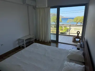 a bedroom with a bed and a large window at Seashore Happiness Apartments in Porto Rafti