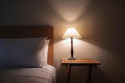 a lamp on a night stand next to a bed at Family Apt in Glyfada-Kyprou, by Comfortbnb in Athens