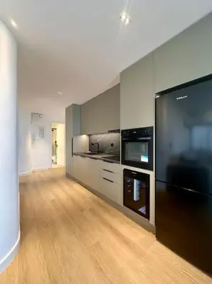 a large kitchen with black appliances and wooden floors at BlueMotion - PortHub Α1 in Piraeus