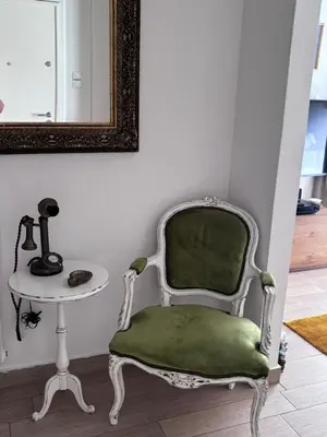a green chair next to a table and a mirror at House Of Joy in Athens