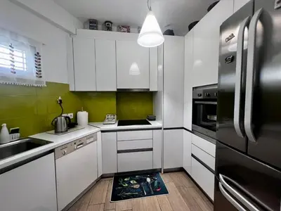 a kitchen with white cabinets and a black refrigerator at House Of Joy in Athens