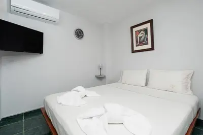 a white bed in a room with a tv at Panos Marina Apartment P1 in Porto Rafti