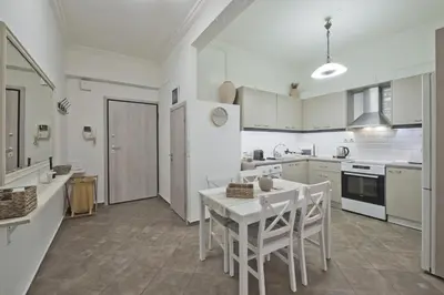 a kitchen with white cabinets and a table and chairs at Irida Stylish, Cozy, Fully Equipped Apt in Piraeus