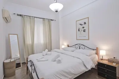 a bedroom with a large white bed and a mirror at Irida Stylish, Cozy, Fully Equipped Apt in Piraeus