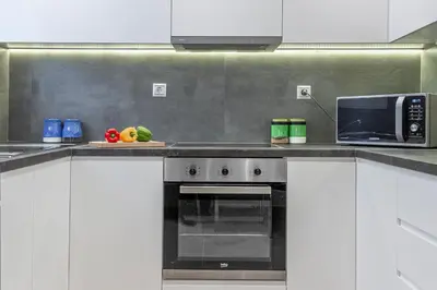 a kitchen with white cabinets and a black microwave at Lemon Tree House Varkiza in Vari