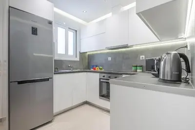 a kitchen with white cabinets and a stainless steel refrigerator at Lemon Tree House Varkiza in Vari