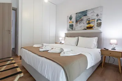 a bedroom with a large white bed with two towels on it at Lemon Tree House Varkiza in Vari