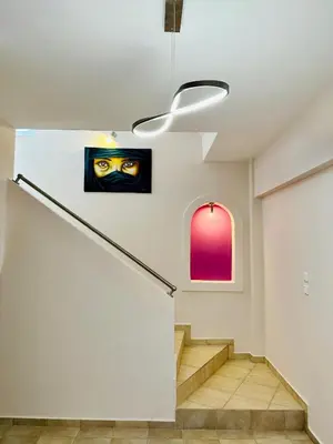 a staircase with a painting of a mask on the wall at Airfenos - Athens Riviera in Anavissos