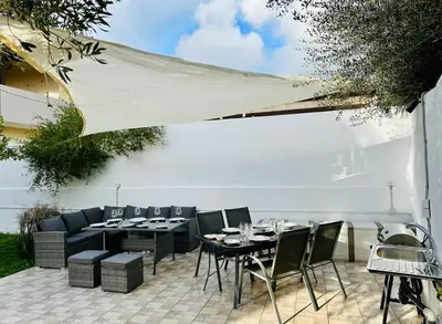 a patio with a table and chairs and a white wall at Airfenos - Athens Riviera in Anavissos