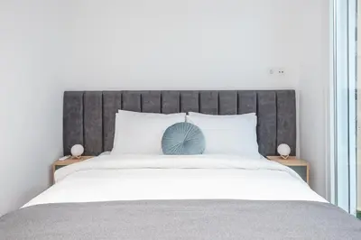 a bedroom with a large bed with a gray headboard at Seaside Corner Kastella Getaway in Piraeus