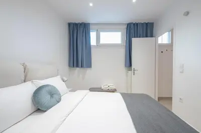 a bedroom with a white bed with a blue pillow at Seaside Corner Kastella Getaway in Piraeus