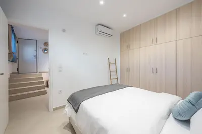 a white bedroom with a bed and a staircase at Seaside Corner Kastella Getaway in Piraeus