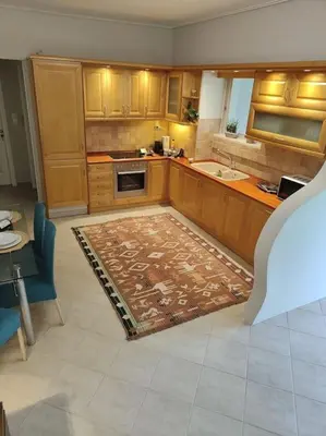a kitchen with wooden cabinets and a rug on the floor at Lefkothea's house in Athens