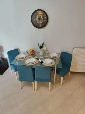 a dining room table with blue chairs and a clock at Lefkothea's house in Athens