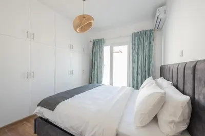 a bedroom with a bed with white sheets and a window at Kastela's Harbor Retreat with Jacuzzi in Piraeus