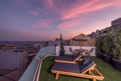 a balcony with two chairs and a table on the grass at Sea Breeze Suite with Jacuzzi in Piraeus