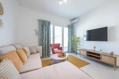 a living room with a couch and a flat screen tv at Sea Breeze Suite with Jacuzzi in Piraeus