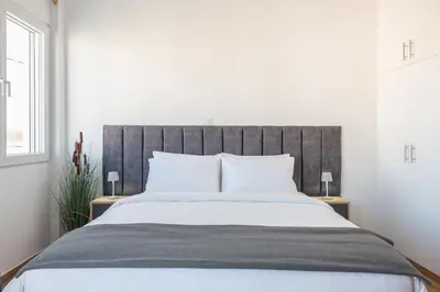 a bedroom with a large bed with white sheets at Sea Breeze Suite with Jacuzzi in Piraeus