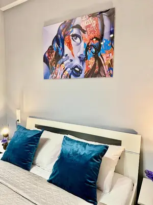 a painting hangs above a bed with blue pillows at Victoria Secret Suite greendom in Athens