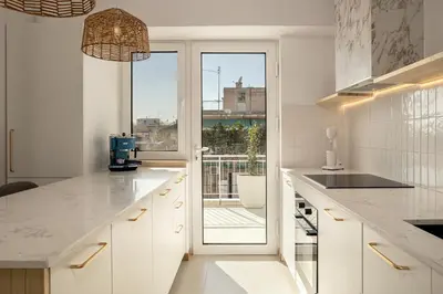 a kitchen with white cabinets and a large window at Victoria Luxury Suite - Private Jacuzzi & Terrace in Athens