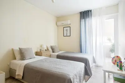two beds in a white room with a window at Faliro Riviera Seaview flat in Athens