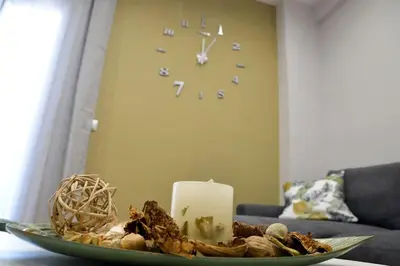 a table with a candle and a clock in a living room at Dream apartment in Kallithea in Athens