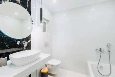 a white bathroom with a sink and a mirror at Hidden Treasure of Koukaki in Athens