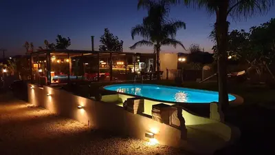 a swimming pool with lights next to a house at Villa Vravrona Tower & Suites in Markopoulo
