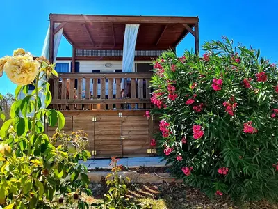 a house with a wooden porch with pink flowers at Villa Vravrona Tower & Suites in Markopoulo