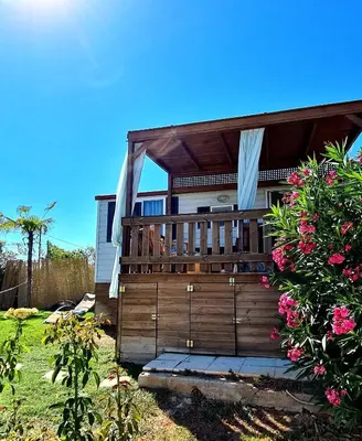 a house with a wooden deck with pink flowers at Villa Vravrona Tower & Suites in Markopoulo