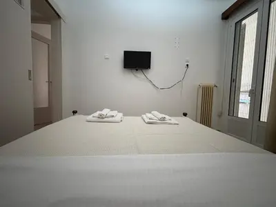 a white room with a bed with two towels on it at Οικογενειακό Διαμέρισμα στην Αθήνα in Athens