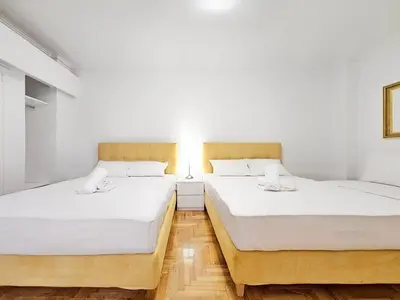 two beds in a room with white walls and wooden floors at Athens Prestige Suite Apartment in Athens