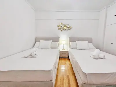 two beds in a room with white walls and wooden floors at Athens Prestige Suite Apartment in Athens