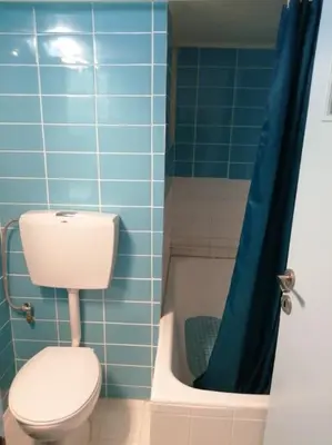 a blue tiled bathroom with a toilet and a tub at 8' από Μετρό,Ντυνάν,Παίδων,Λαϊκό in Athens