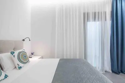 a bedroom with a bed with blue curtains and a window at Cozy apartment in a new building apartment 5 in Piraeus