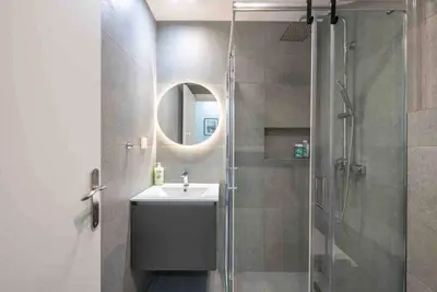 a bathroom with a sink and a shower with a mirror at Cozy apartment in a new building apartment 5 in Piraeus