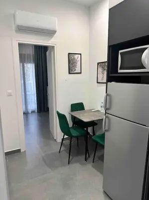 a kitchen with a refrigerator and a table with green chairs at Cozy apartment in a new building apartment 5 in Piraeus