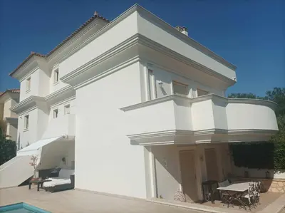 a white house with a balcony and a patio at Guest apartment within a villa in Lagonissi in Kalívia Thorikoú