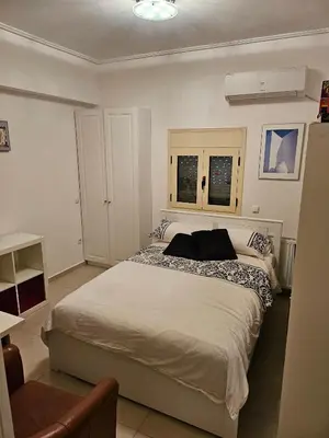 a bedroom with a bed and two windows at Guest apartment within a villa in Lagonissi in Kalívia Thorikoú
