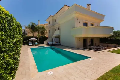 a villa with a swimming pool in front of a house at Guest apartment within a villa in Lagonissi in Kalívia Thorikoú