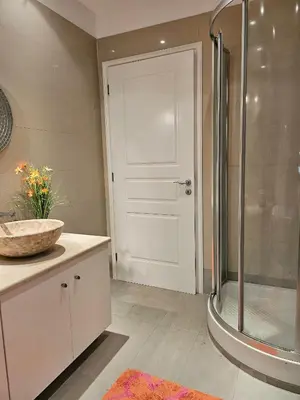 a bathroom with a shower and a sink and a door at Guest apartment within a villa in Lagonissi in Kalívia Thorikoú