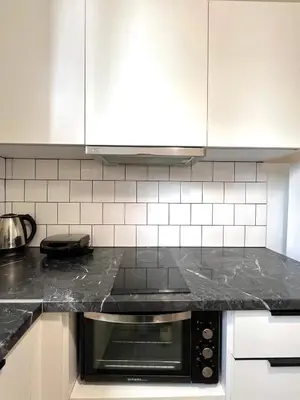 a kitchen with white cabinets and a black counter top at Mosaikon Guesthouses #Miltiadou Str in Athens