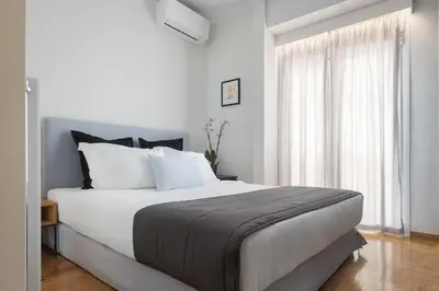 a white bedroom with a large bed and a window at Acropolis Vibe Residence in Athens