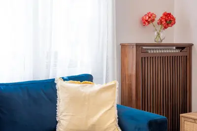 a blue couch with a pillow and a vase of flowers at Agora Apartment Plaka and Acropolis area in Athens