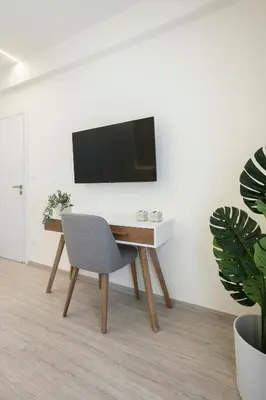 a desk with a chair and a television on a wall at Deluxe Apartment in Kallithea with Balcony & Wifi in Athens